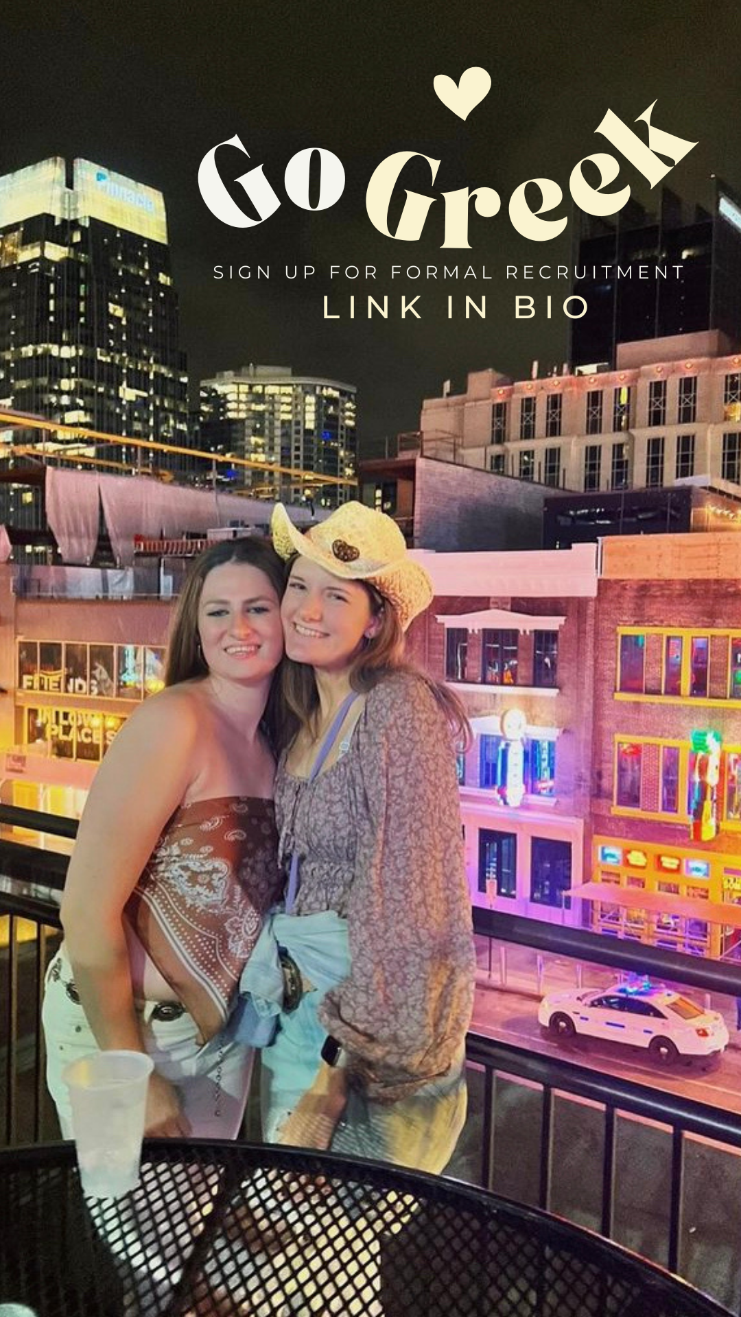 Two girls smiling at camera. It it night time outside and there are lots of shining lights. Words say go greek and link in bio.